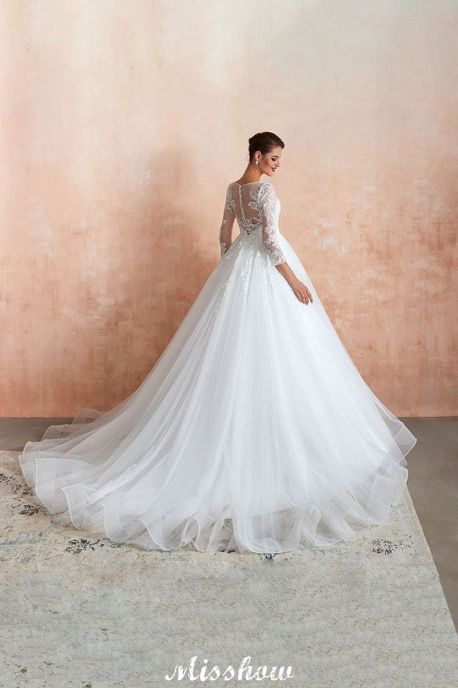 Robe de bal romantique en dentelle à manches longues, entièrement recouverte de tulle, boutons recouverts, coupe trapèze, traîne courte.