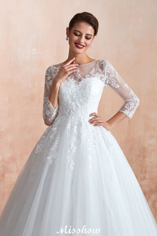 Robe de bal romantique en dentelle à manches longues, entièrement recouverte de tulle, boutons recouverts, coupe trapèze, traîne courte.