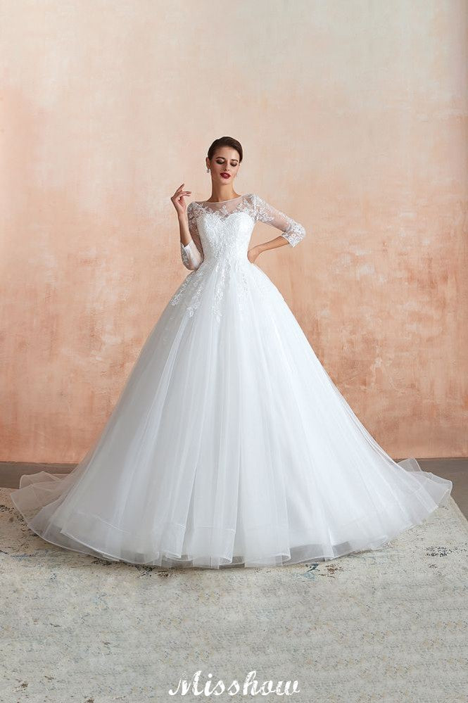 Robe de bal romantique en dentelle à manches longues, entièrement recouverte de tulle, boutons recouverts, coupe trapèze, traîne courte.