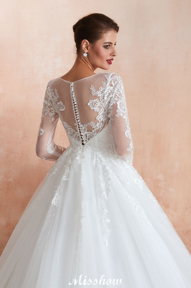 Robe de bal romantique en dentelle à manches longues, entièrement recouverte de tulle, boutons recouverts, coupe trapèze, traîne courte.