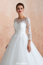 Robe de bal romantique en dentelle à manches longues, entièrement recouverte de tulle, boutons recouverts, coupe trapèze, traîne courte.
