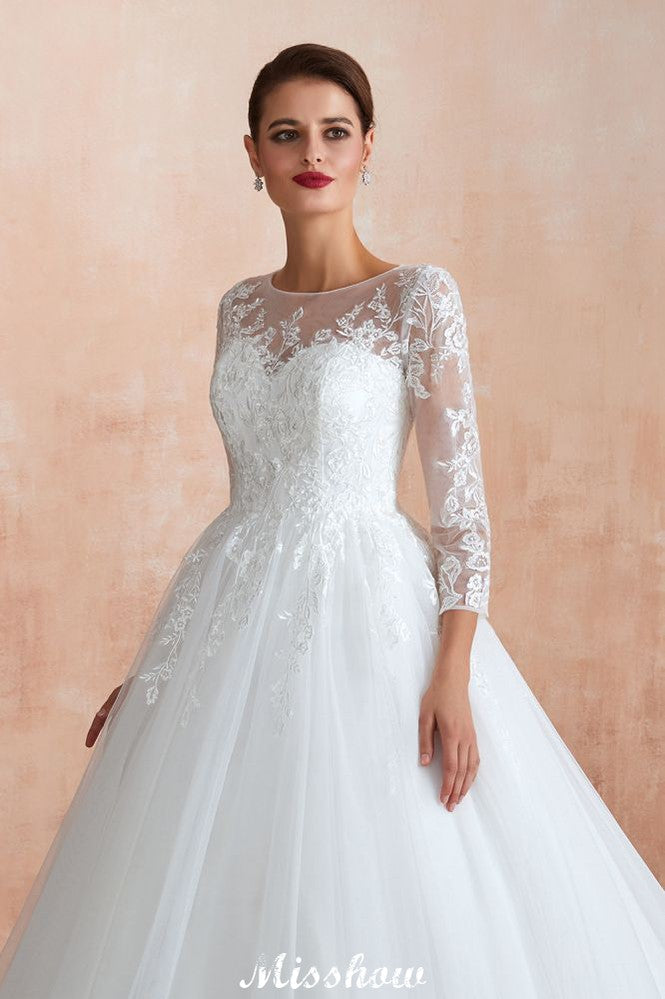 Robe de bal romantique en dentelle à manches longues, entièrement recouverte de tulle, boutons recouverts, coupe trapèze, traîne courte.