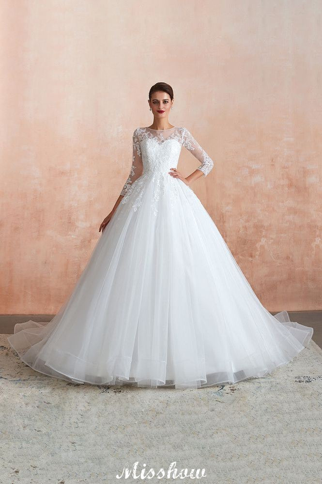 Robe de bal romantique en dentelle à manches longues, entièrement recouverte de tulle, boutons recouverts, coupe trapèze, traîne courte.