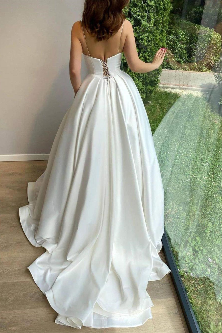 Robe de mariée romantique à fines bretelles blanches et applications de dentelle, coupe trapèze, sans manches, avec traîne. 