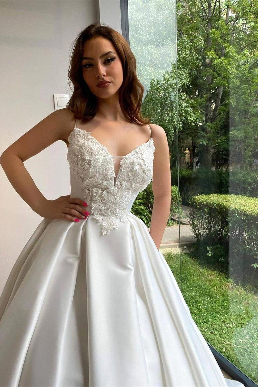 Robe de mariée romantique à fines bretelles blanches et applications de dentelle, coupe trapèze, sans manches, avec traîne. 