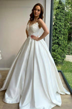 Robe de mariée romantique à fines bretelles blanches et applications de dentelle, coupe trapèze, sans manches, avec traîne. 