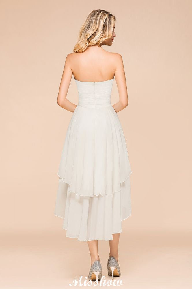 Robe de demoiselle d'honneur romantique blanche/ivoire à décolleté cœur asymétrique sans manches, idéale pour un mariage de plage.