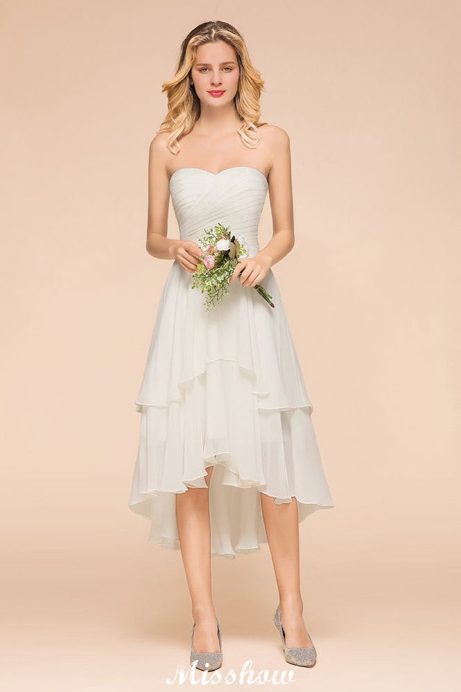 Vestido de dama de honor romántico blanco/marfil con escote corazón y corte asimétrico, sin mangas, ideal para bodas en la playa.