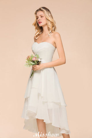 Vestido de dama de honor romántico blanco/marfil con escote corazón y corte asimétrico, sin mangas, ideal para bodas en la playa.