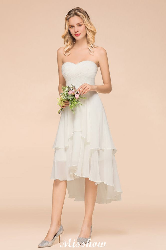 Robe de demoiselle d'honneur romantique blanche/ivoire à décolleté cœur asymétrique sans manches, idéale pour un mariage de plage.