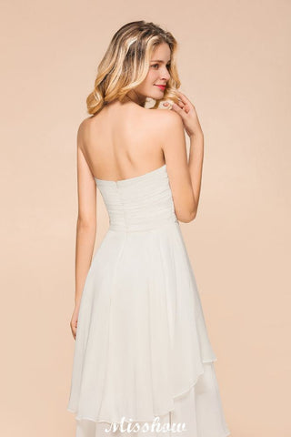 Vestido de dama de honor romántico blanco/marfil con escote corazón y corte asimétrico, sin mangas, ideal para bodas en la playa.