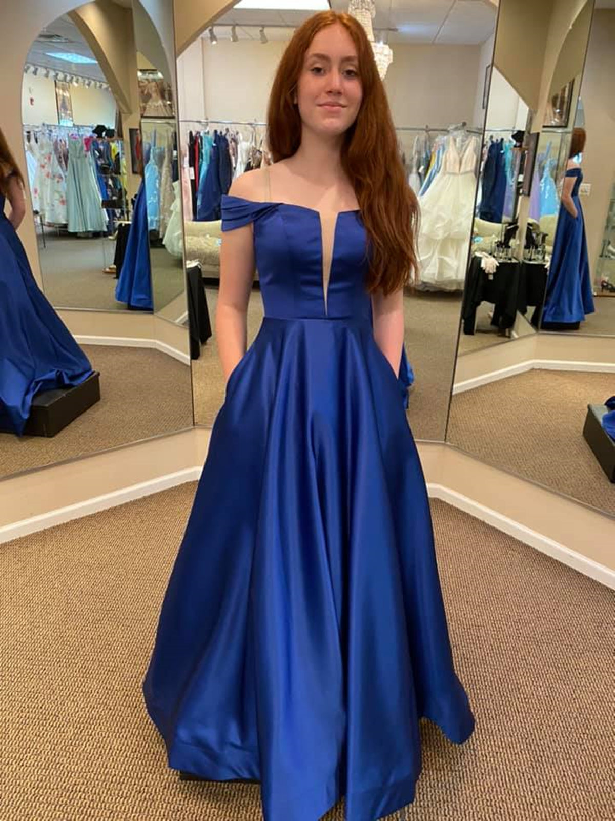 Vestido de fiesta largo azul real de satén, corte en A, hombros descubiertos y bolsillos.