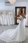 Robe de mariée longue et sexy, coupe trapèze, décolleté cœur, bretelles spaghetti, dos nu et traîne chapelle.