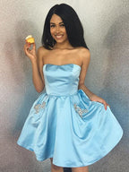 Robe de bal courte trapèze sans bretelles en satin ornée de perles et de poches