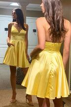 Robe de bal courte jaune satinée, coupe trapèze, col en V, dos nu et poches