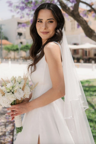 Vestido de novia sencillo, largo, color marfil, corte en A, sin mangas, de tul, con tirantes y abertura.