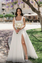 Vestido de novia sencillo, largo, color marfil, corte en A, sin mangas, de tul, con tirantes y abertura.