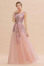 Robe de soirée longue rose poudré sans manches, coupe trapèze, ornée d'appliqués de tulle et de dentelle.