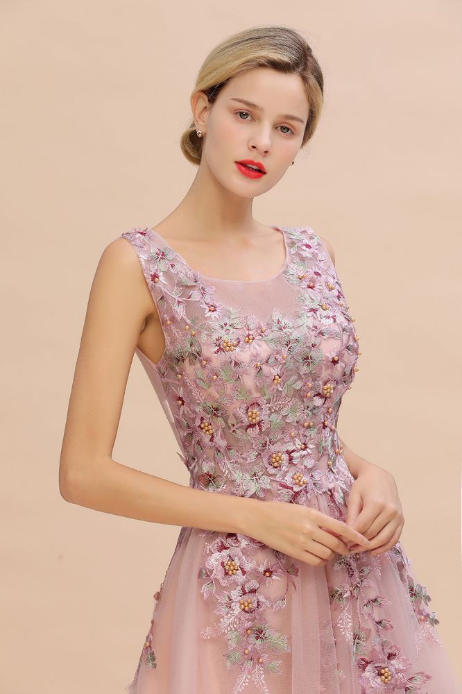 Robe de soirée longue rose poudré sans manches, coupe trapèze, ornée d'appliqués de tulle et de dentelle.