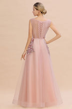 Robe de soirée longue rose poudré sans manches, coupe trapèze, ornée d'appliqués de tulle et de dentelle.