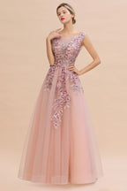 Robe de soirée longue rose poudré sans manches, coupe trapèze, ornée d'appliqués de tulle et de dentelle.