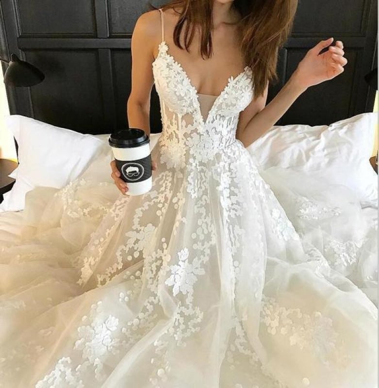 Robe de mariée élégante en tulle avec dentelle, bretelles spaghetti, décolleté en V et traîne, idéale pour la plage. 