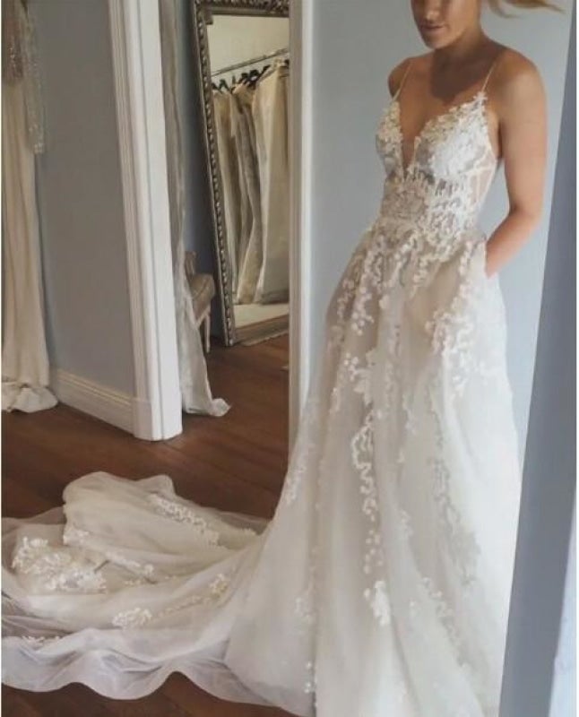 Robe de mariée élégante en tulle avec dentelle, bretelles spaghetti, décolleté en V et traîne, idéale pour la plage. 