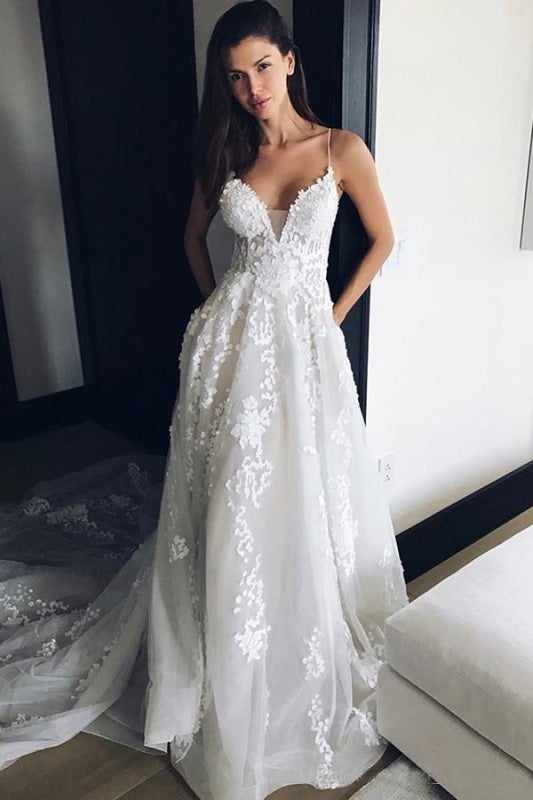 Robe de mariée élégante en tulle avec dentelle, bretelles spaghetti, décolleté en V et traîne, idéale pour la plage. 