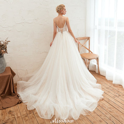 Vestido de novia color champán con tirantes finos, escote en V pronunciado y espalda descubierta