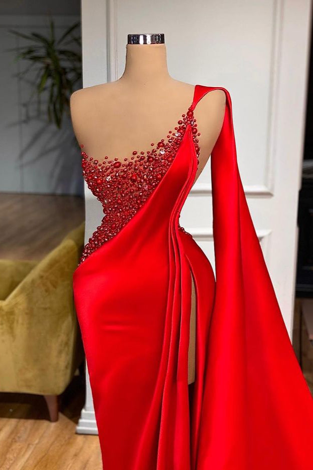 Robe de soirée sirène fendue jusqu'à la cuisse, ornée de pierres rouges et sans manches.