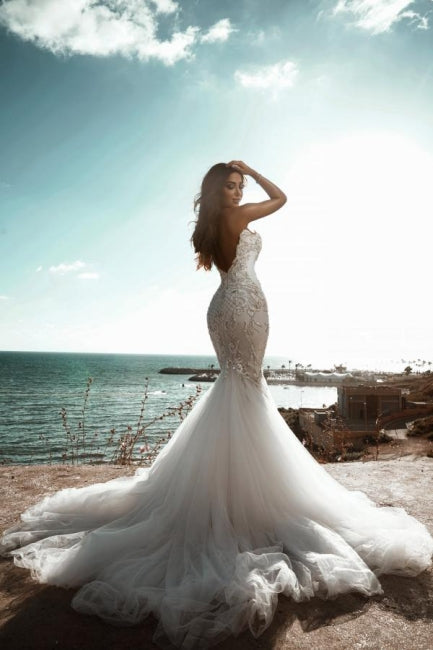Robe de mariée sirène ornée de perles et décolleté en cœur, sans manches, en tulle. 