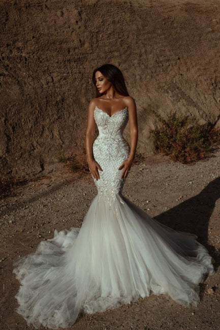 Robe de mariée sirène ornée de perles et décolleté en cœur, sans manches, en tulle. 
