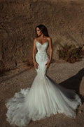 Robe de mariée sirène ornée de perles et décolleté en cœur, sans manches, en tulle. 