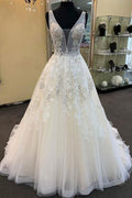 Robe de mariée unique longue en tulle et dentelle perlée, col en V, coupe trapèze.