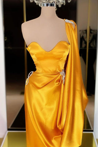 Robe de bal longue unique en or jaune, ornée de volants et asymétrique.