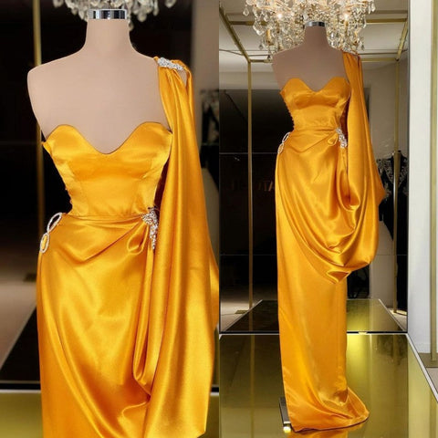 Robe de bal longue unique en or jaune, ornée de volants et asymétrique.