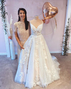 Robe de mariée vintage longue trapèze à fines bretelles, ornée d'appliqués de dentelle et d'une traîne.