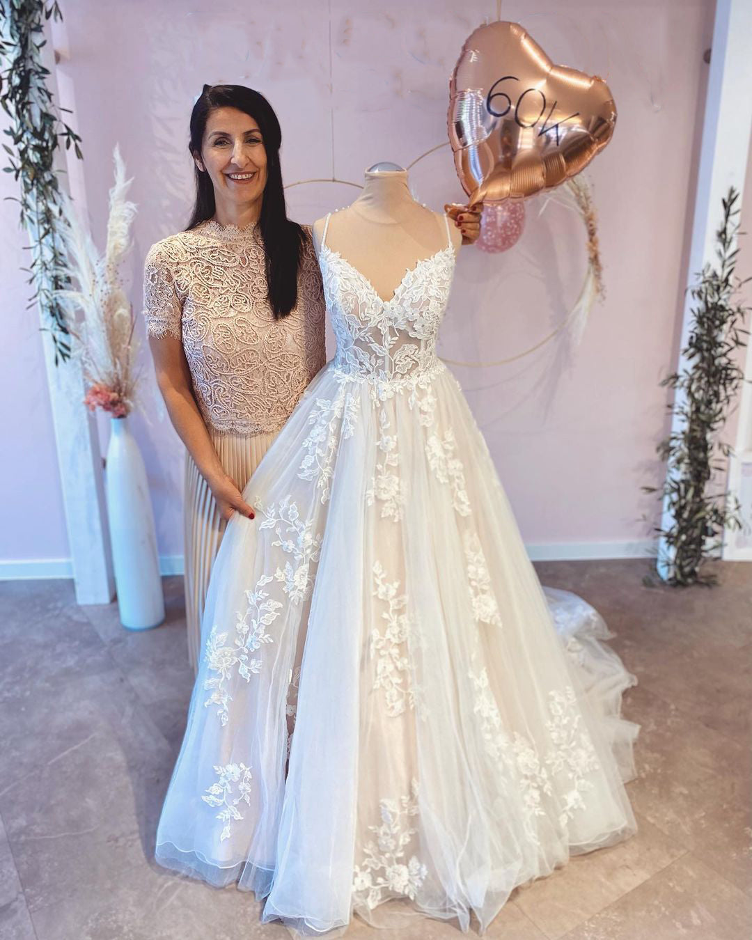 Robe de mariée vintage longue trapèze à fines bretelles, ornée d'appliqués de dentelle et d'une traîne.