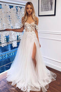 Robe de mariée blanche bohème longue en dentelle, coupe trapèze, épaules dénudées et fente.