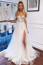 Robe de mariée blanche bohème longue en dentelle, coupe trapèze, épaules dénudées et fente.