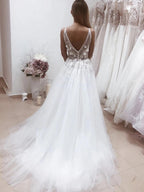 Robe de mariée blanche longue trapèze à dos nu et décolleté en V ornée d'appliqués de dentelle
