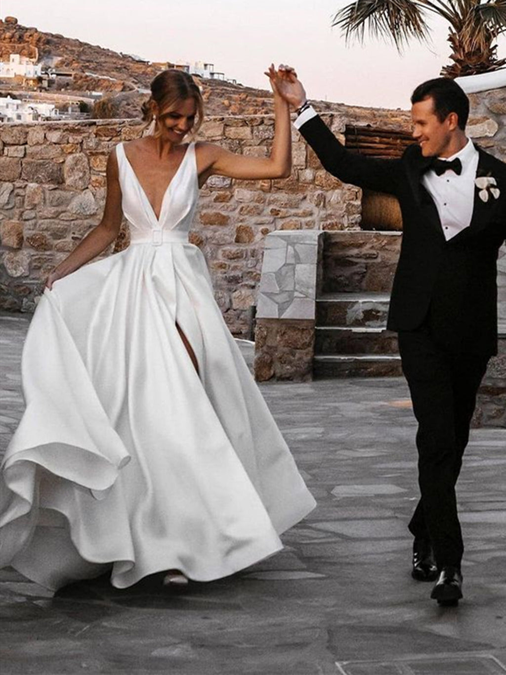 Robe de mariée blanche longue en satin, coupe trapèze, col en V, dos nu et fente.