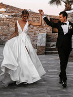 Robe de mariée blanche longue en satin, coupe trapèze, col en V, dos nu et fente.