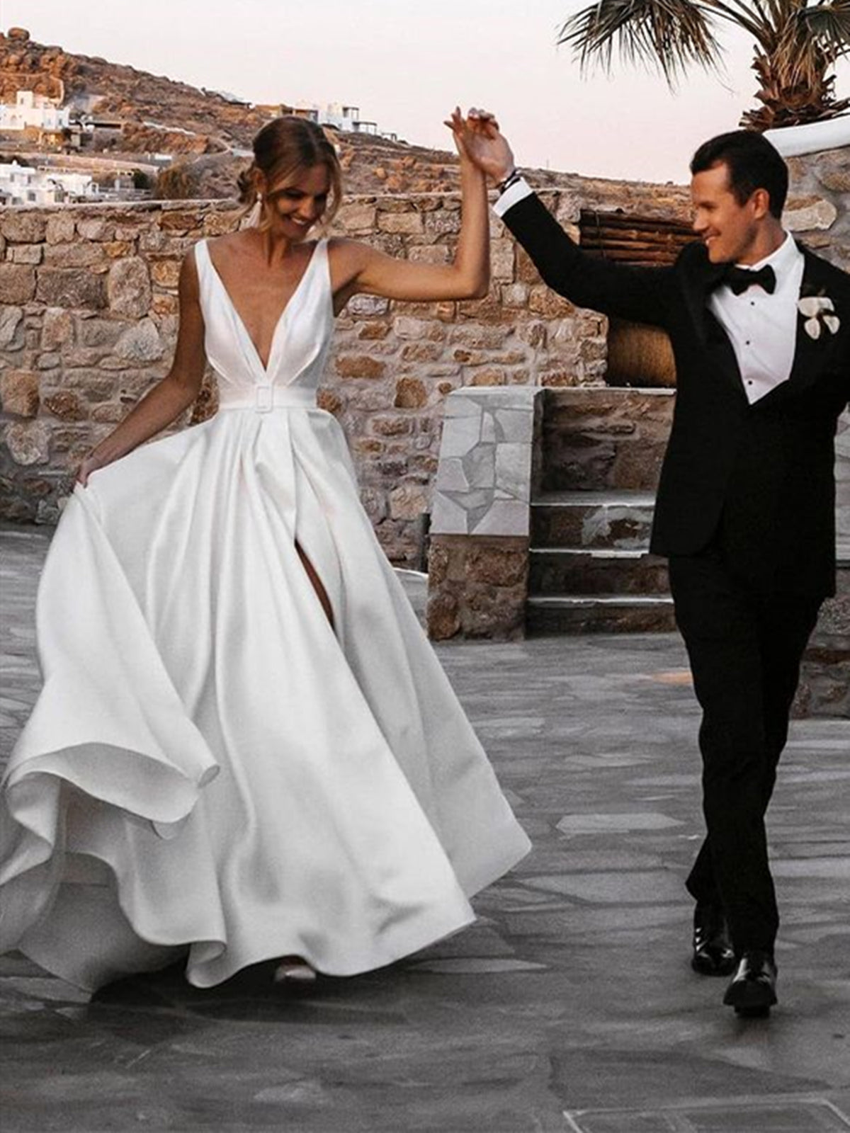 Robe de mariée blanche longue en satin, coupe trapèze, col en V, dos nu et fente.