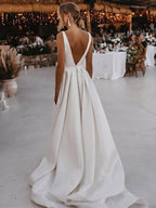 Robe de mariée blanche longue en satin, coupe trapèze, col en V, dos nu et fente.