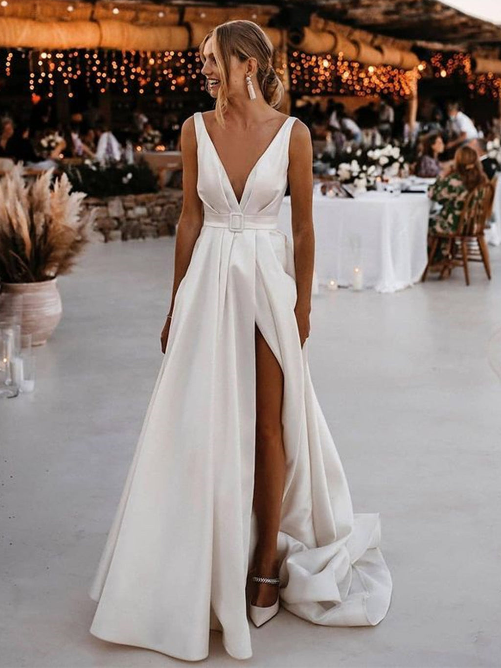 Robe de mariée blanche longue en satin, coupe trapèze, col en V, dos nu et fente.