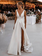 Robe de mariée blanche longue en satin, coupe trapèze, col en V, dos nu et fente.