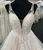 Robe de mariée longue à volants en tulle blanc, col en V et dos nu. 