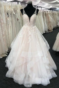 Robe de mariée longue à volants en tulle blanc, col en V et dos nu. 
